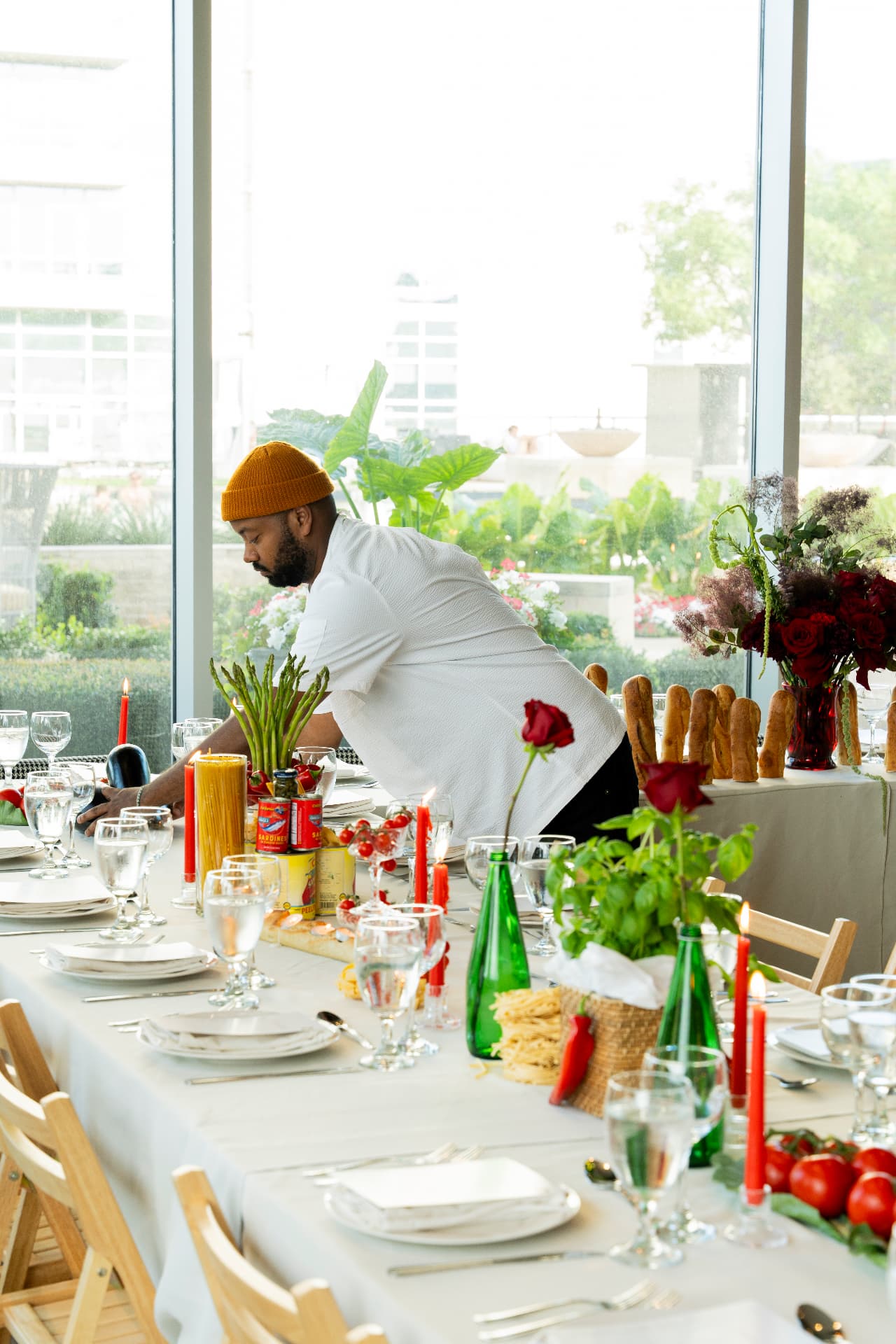 Taru studio member setting a long table with florals, candles, and produce during production